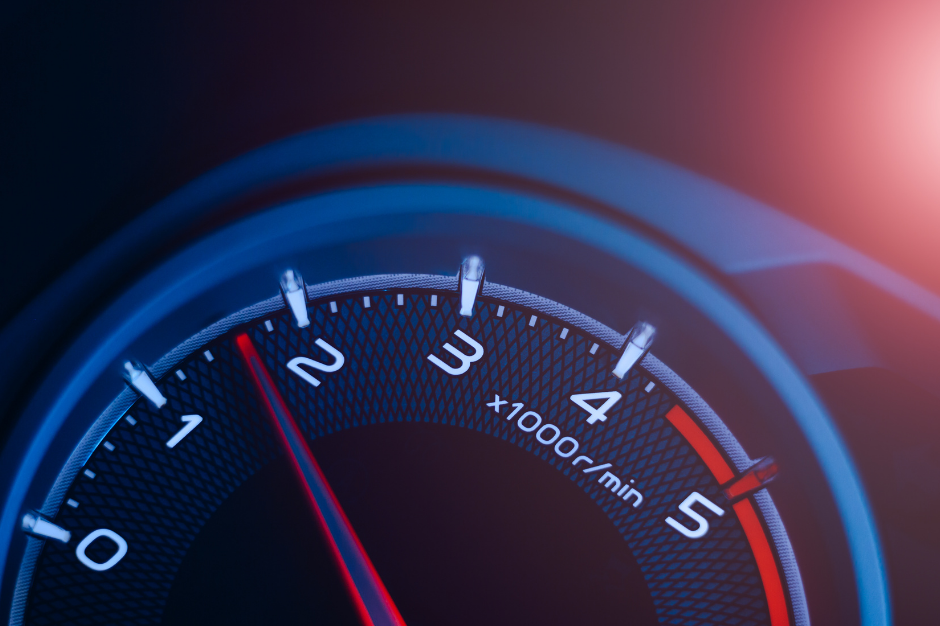 Close-up of a car tachometer with a red needle pointing at 2, indicating engine speed in thousands of revolutions per minute (x1000 r/min), with blue and red lighting effects.