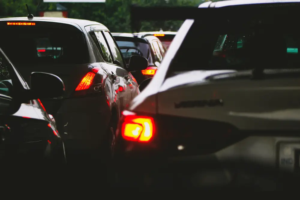 Cars are stopped in traffic, with brake lights glowing red. The vehicles are closely packed together, suggesting congestion or a traffic jam. The photo is taken from a low angle, capturing the rear and sides of the cars.